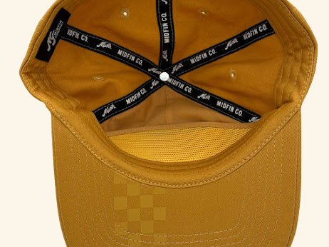 Yellow cap with checkered pattern on the brim and black adjustable strap on a white background